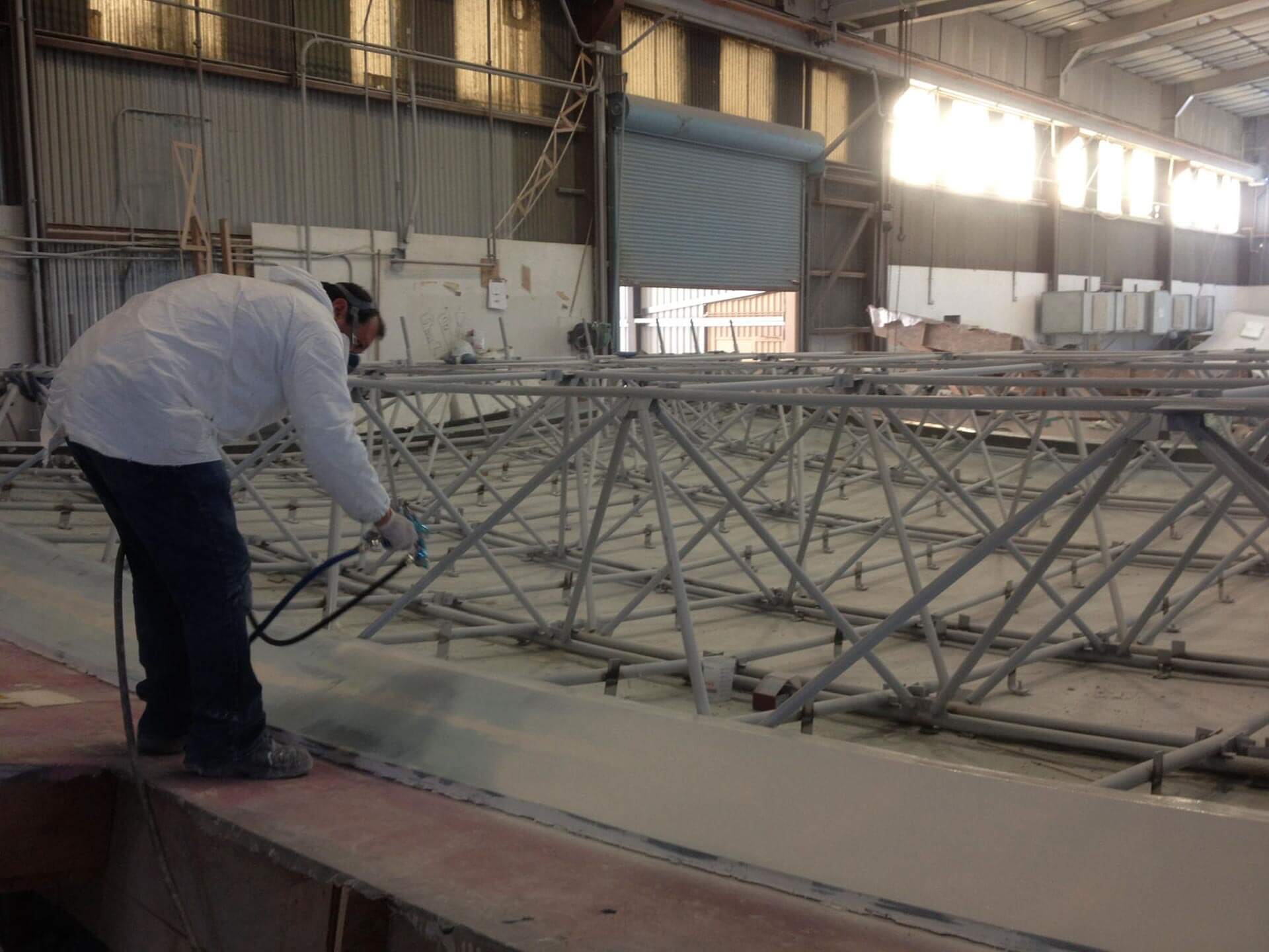 Man spraying insulation on the backside of an acoustic panel